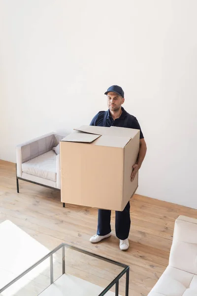 Déménageur tenant une grande boîte en carton dans l'appartement — Photo de stock