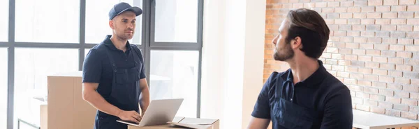 Mover typing on laptop while looking at colleague, banner — Stock Photo