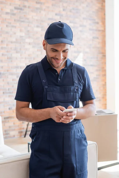 Trabajador feliz en overoles aceptar el orden en el teléfono móvil - foto de stock