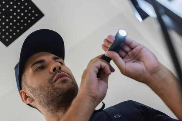 Vista a basso angolo di idraulico utilizzando torcia elettrica in bagno — Foto stock