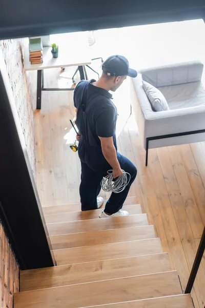 Vue grand angle de l'ouvrier avec des outils et des fils marchant en bas dans un appartement moderne — Photo de stock