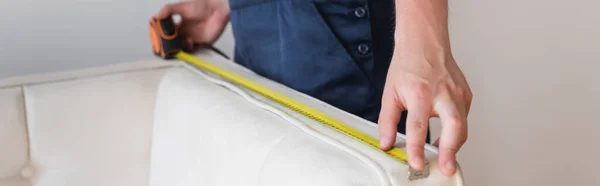 Cropped view of handyman measuring white couch, banner — Stock Photo