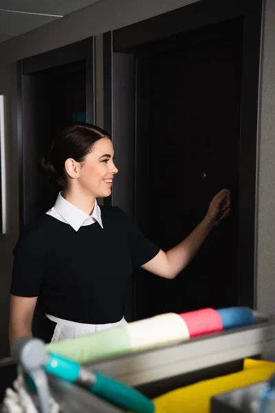 Empregada alegre batendo porta no hotel — Fotografia de Stock