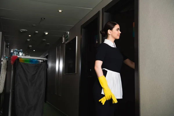 Jovem sorrindo empregada batendo porta no corredor do hotel — Fotografia de Stock