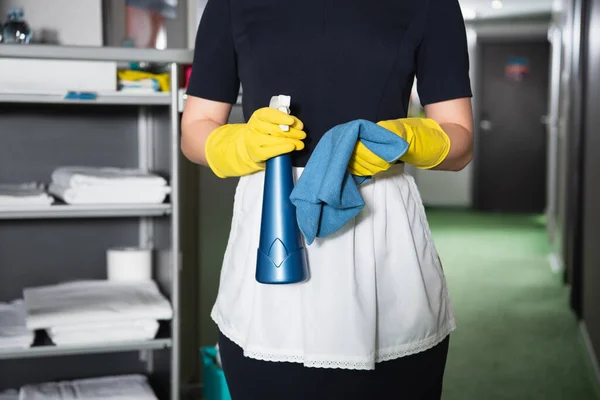 Cropped view of chambermaid in rubber gloves holding holding spray bottle and rag — Stock Photo