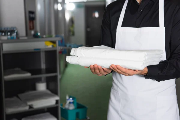 Cropped view of housekeeper holding clean bed sheets — Stock Photo