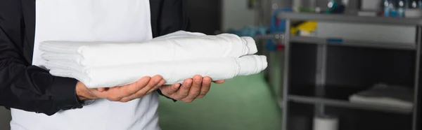 Cropped view of housekeeper holding clean bed sheets, banner — Stock Photo