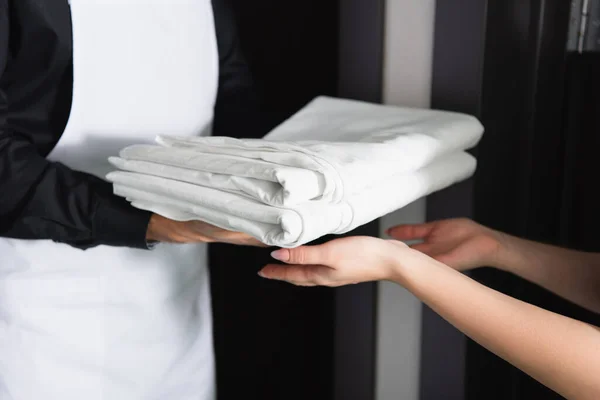Cropped view of maid housekeeper giving clean bed sheets to maid — Stock Photo