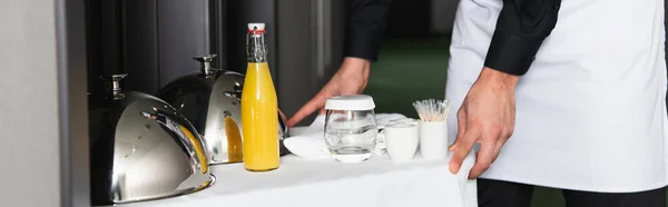 Vista recortada del camarero en bandeja de entrega delantal con cloche y bebidas, pancarta - foto de stock