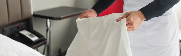 Partial view of housekeeper changing bedding in hotel room, banner — Stock Photo