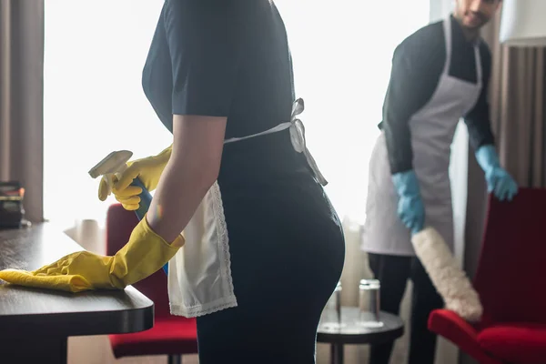 Vista recortada de amas de llaves haciendo limpieza en habitación de hotel moderna con suministros de limpieza - foto de stock