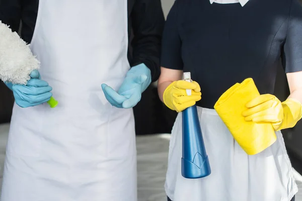 Partial view of housekeepers holding cleaning supplies — Stock Photo