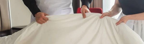 Cropped view of housekeepers changing bedding in hotel room, banner — Stock Photo