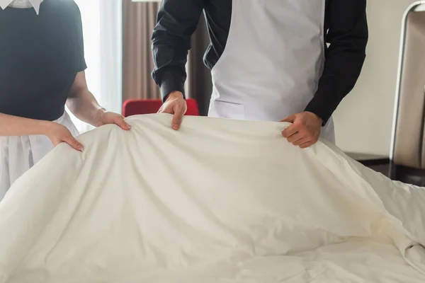 Ausgeschnittene Ansicht von Haushälterinnen, die Bettwäsche im Hotelzimmer wechseln — Stockfoto