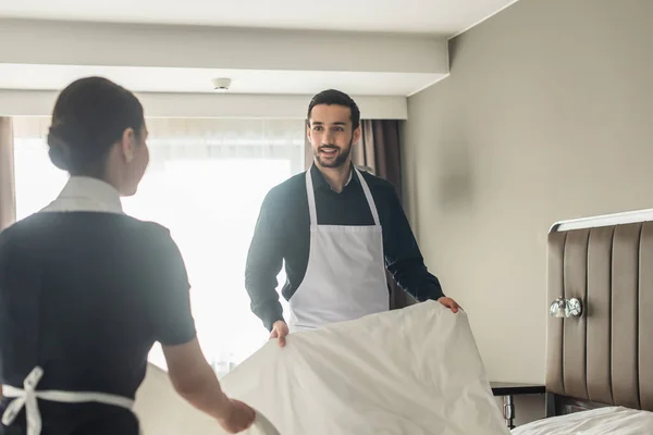 Donas de casa felizes mudando de roupa de cama no quarto de hotel — Fotografia de Stock