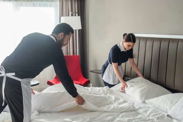 Femmes de ménage changeant de literie dans la chambre d'hôtel moderne — Photo de stock