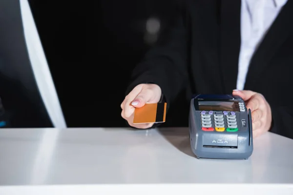 Vista cortada de administrador segurando cartão de crédito perto do terminal de pagamento no hotel — Fotografia de Stock