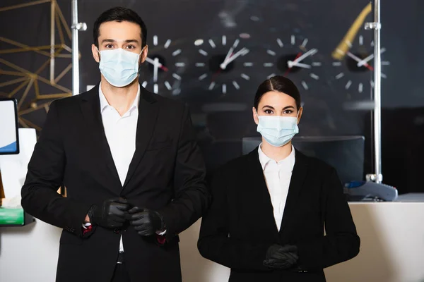 Administradores em máscaras médicas e luvas de látex perto da recepção — Fotografia de Stock