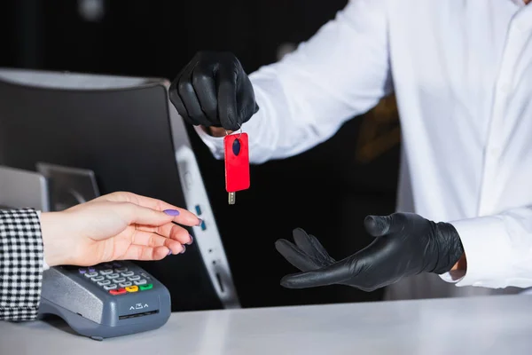 Vue recadrée de la réceptionniste en gants de latex donnant la clé de chambre à l'invité — Photo de stock