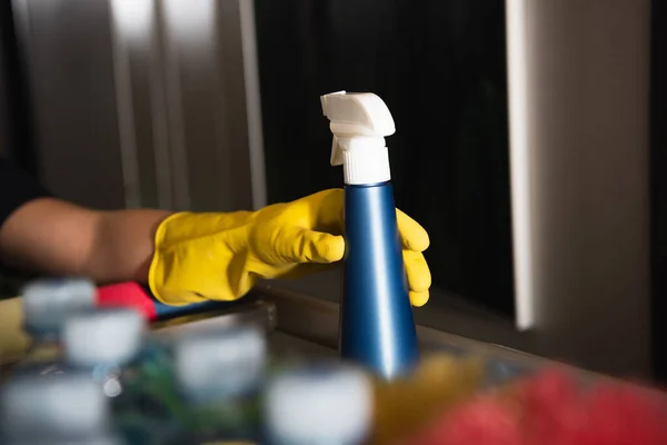 Cropped view of maid in rubber glove reaching spray bottle — Stock Photo