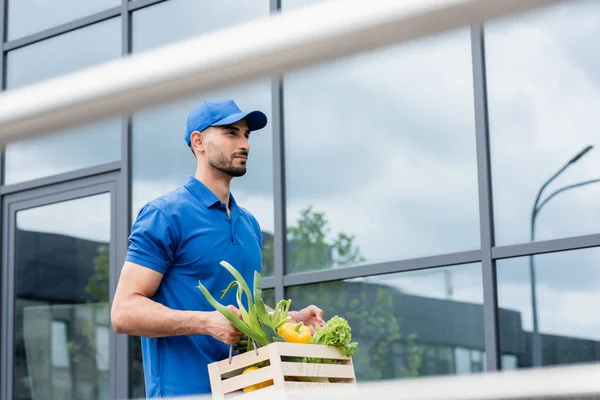 Arabian courier holding box with vegetables outdoors — Stock Photo