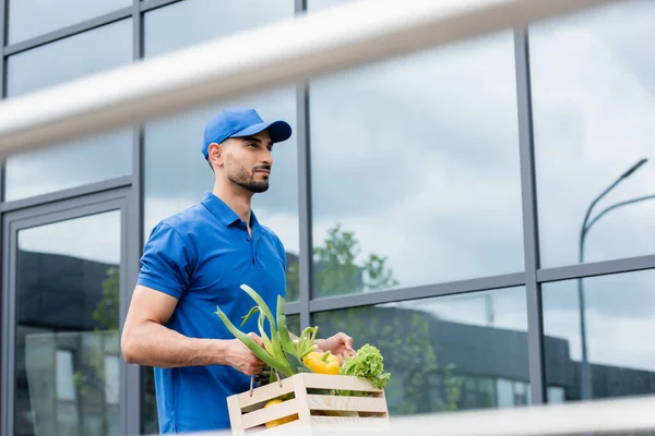 Arabischer Kurier hält Box mit Gemüse im Freien — Stockfoto