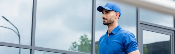 Mensajero musulmán con gorra cerca del edificio al aire libre, pancarta - foto de stock