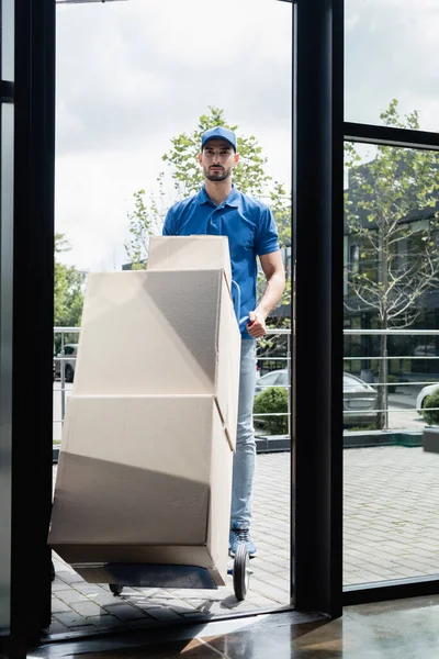 Arabischer Kurier mit Kisten in der Nähe von Haustür — Stockfoto