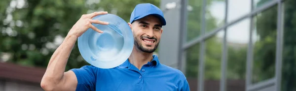 Mensajero musulmán positivo con botella de agua al aire libre, pancarta - foto de stock