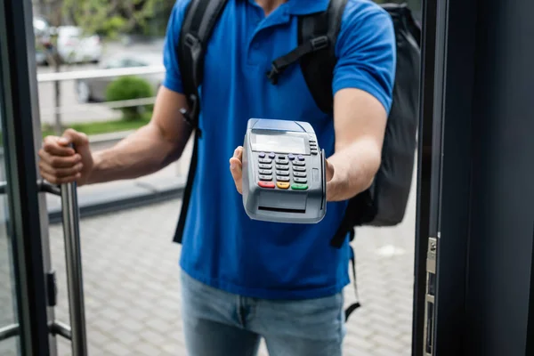 Ausgeschnittene Ansicht des Zahlungsterminals in der Hand eines verschwommenen Kuriers in der Nähe der Tür — Stockfoto