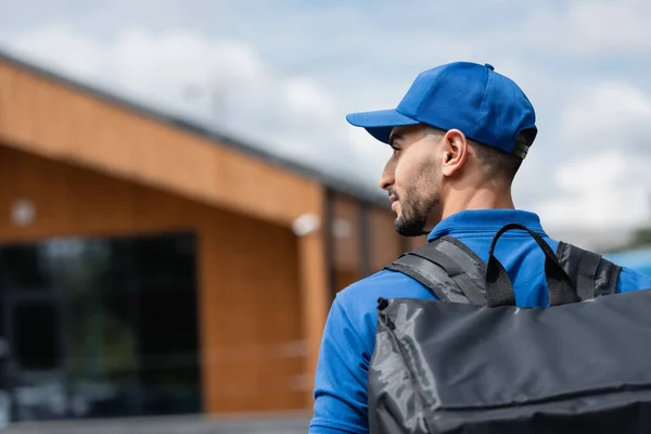 Side view of muslim deliveryman in uniform with thermo backpack outdoors — Stock Photo