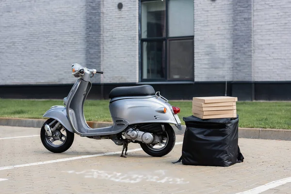 Scooter perto de mochila térmica e caixas de pizza ao ar livre — Fotografia de Stock