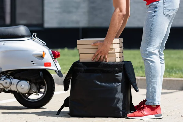 Vue recadrée des colis de messagerie avec pizza près du sac à dos et du scooter thermo — Photo de stock