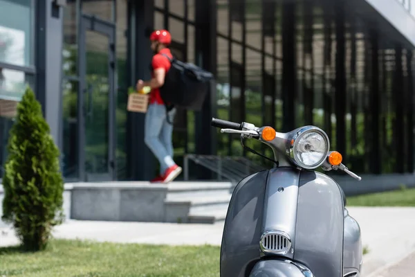 Scooter and blurred courier near building outdoors — Stock Photo