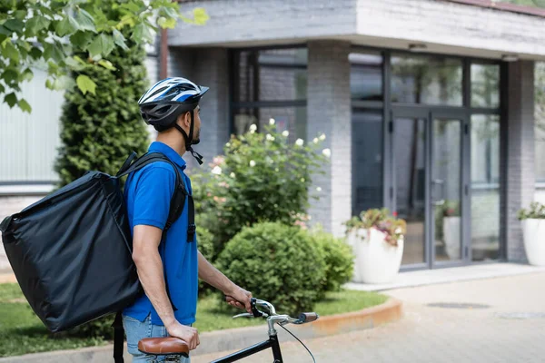 Correio árabe com mochila em pé perto de bicicleta ao ar livre — Fotografia de Stock