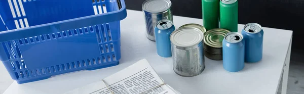 Blechdosen, Zeitungen neben Korb auf Tisch, Banner — Stockfoto