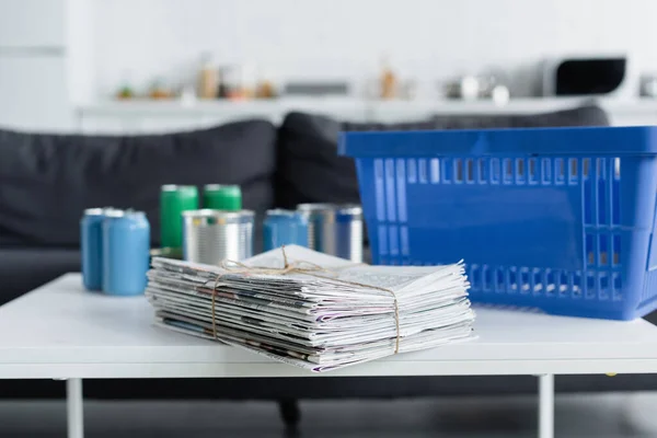 Zeitungen neben verschwommenen Blechdosen und Korb auf dem heimischen Tisch — Stockfoto