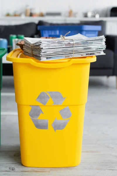 Quotidiani sul cestino con cartello di riciclo a casa — Foto stock