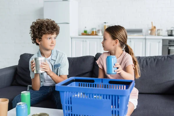 Girl holding blurred tin can near brother and basket at home — Stock Photo