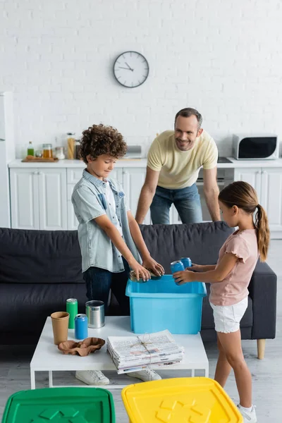 Père souriant debout près des enfants triant les ordures dans la cuisine — Photo de stock