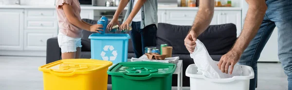 Vista recortada de la familia clasificación de basura en cubos de basura con cartel de reciclaje, pancarta - foto de stock