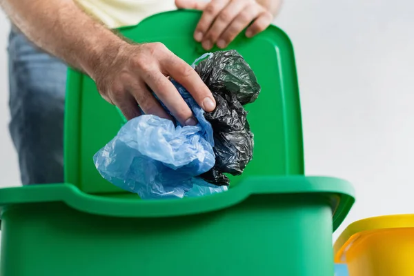 Vista ritagliata di uomo sfocato in possesso di sacchetti di plastica vicino bidone della spazzatura a casa — Foto stock