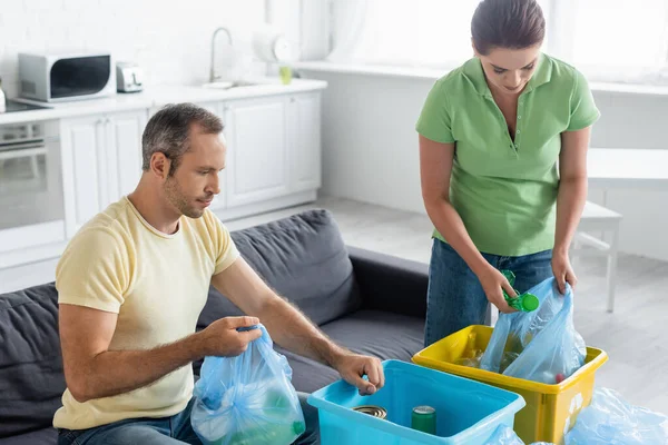 Adult couple with trash bags and boxes sorting garbage in kitchen — Stock Photo