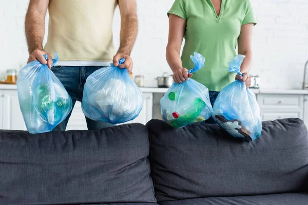Vue recadrée du couple tenant des sacs poubelle dans la cuisine — Photo de stock