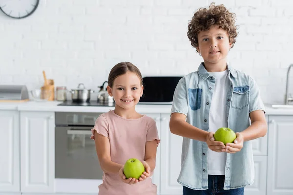 Positivo fratello e sorella che tiene le mele in cucina — Foto stock
