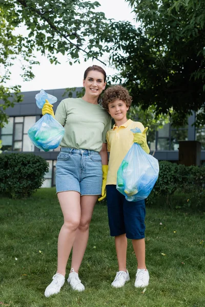 Fröhliche Frau umarmt Sohn mit Müllsack — Stockfoto