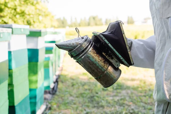 Vue partielle du rucher avec le fumeur d'abeilles près des ruches floues sur le rucher — Photo de stock