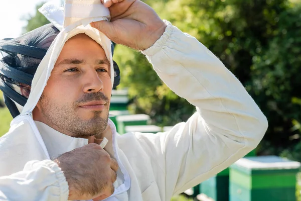 Imkermeister zieht Imkeranzug am Imkerstand aus — Stockfoto