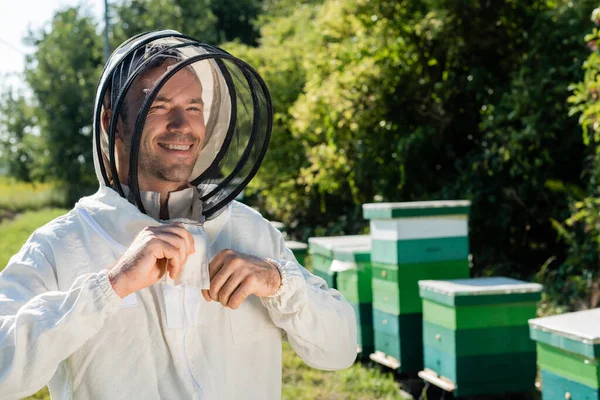 Apiculteur heureux ajustant sa combinaison de protection sur le rucher — Photo de stock