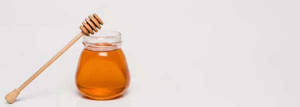 Wooden dipper near jar with honey on white background, banner — Stock Photo